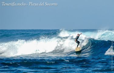 Surfer auf einer Welle vor dem Strand